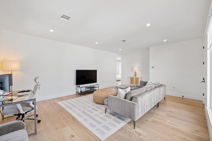 Living area featuring light wood finished floors, recessed lighting, and an office area