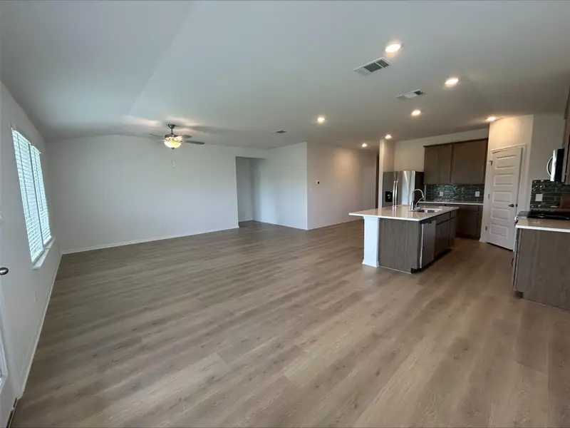 Kitchen with open floor plan, tasteful backsplash, a center island with sink, light wood-style floors, and recessed lighting