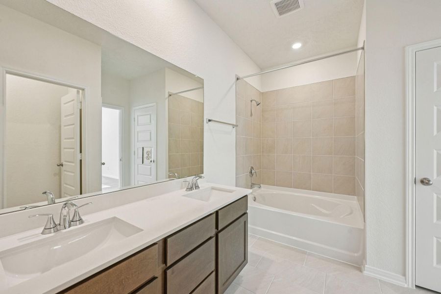 This primary bathroom is definitely move-in ready! Featuring stained cabinets with light countertops, dual vanities, high ceilings, neutral paint, walk-in closet, tub/shower combination with tile surround, sleek and modern finishes.