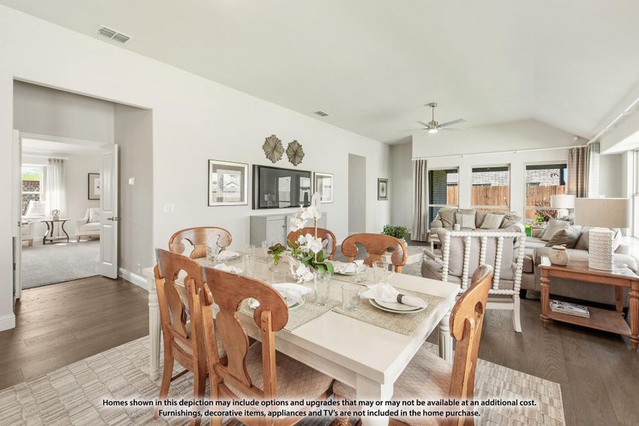 Open-plan dining and living area with white dining table, wood chairs, and vaulted ceiling with ceiling fan Open-plan dining and living area with white dining table, wood chairs, and vaulted ceiling with ceiling fan