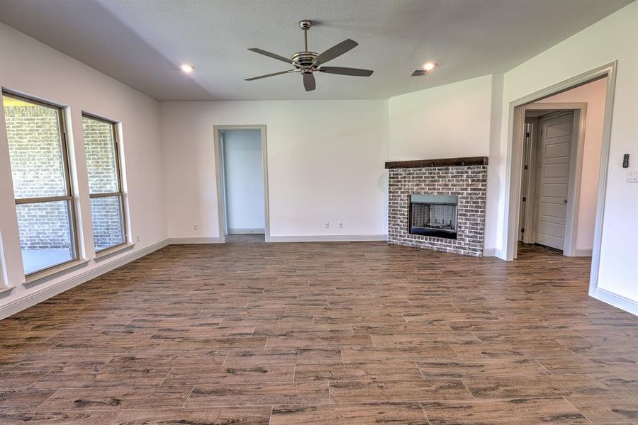 Unfurnished living room with a brick fireplace, recessed lighting, ceiling fan, and wood finished floors Unfurnished living room with a brick fireplace, recessed lighting, ceiling fan, and wood finished floors