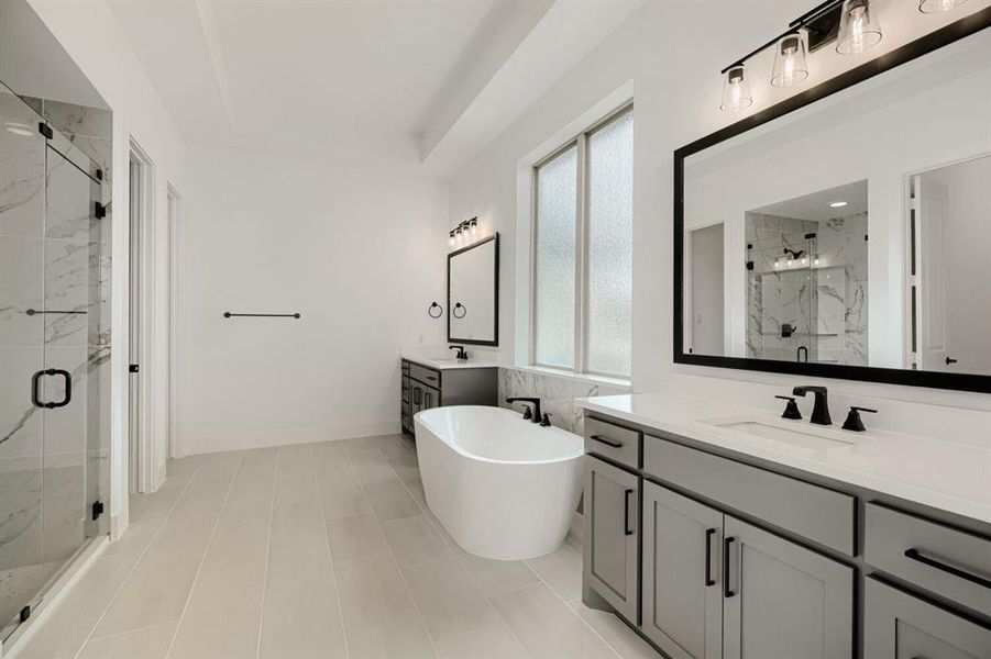 Bathroom with a marble finish shower, two vanities, and a freestanding tub