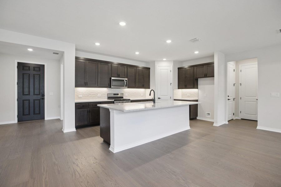Kitchen featuring backsplash, light stone countertops, stainless steel appliances, recessed lighting, and light wood-style floors