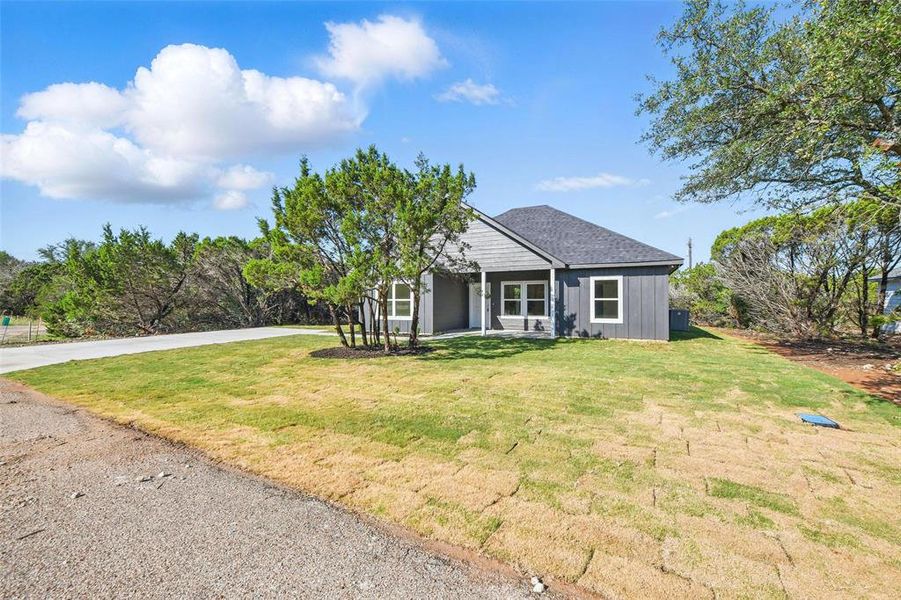 View of front of home featuring a front yard, driveway, and board and batten siding View of front of home featuring a front yard, driveway, and board and batten siding
