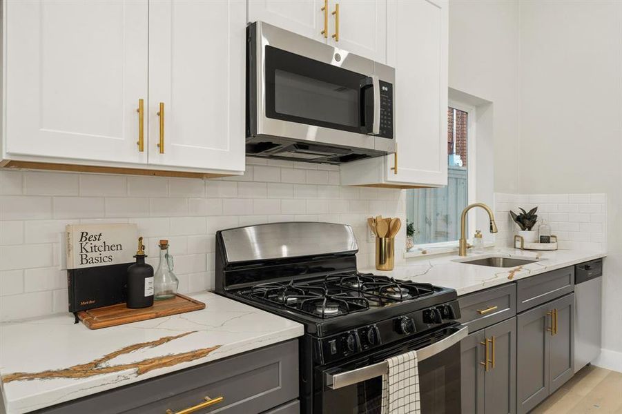 Modern kitchen featuring white upper cabinetry and gray lower cabinetry with gold-toned hardware Modern kitchen featuring white upper cabinetry and gray lower cabinetry with gold-toned hardware