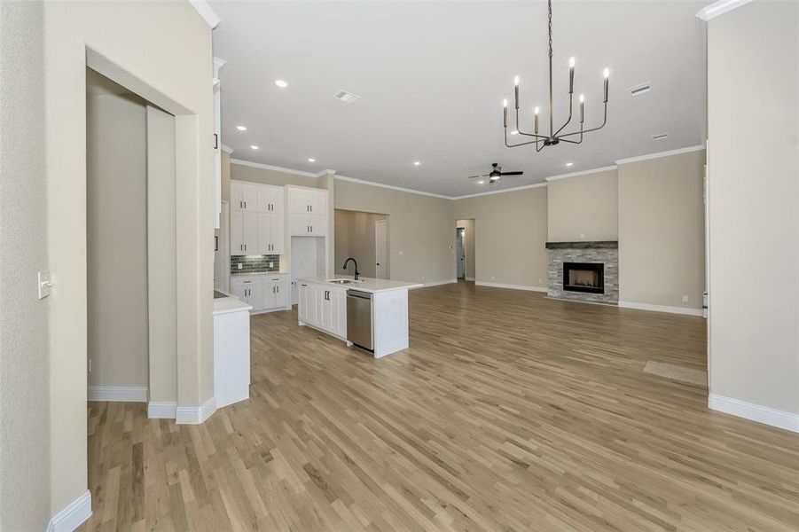 Kitchen with sink, light hardwood / wood-style flooring, a kitchen island with sink, white cabinets, and ceiling fan with notable chandelier