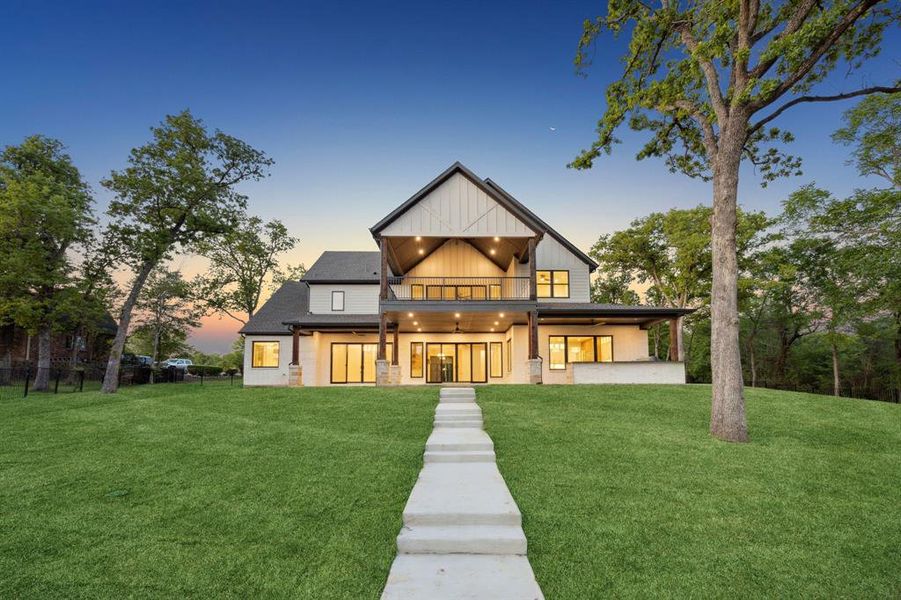 View of front of home featuring board and batten siding, a front yard, and a balcony View of front of home featuring board and batten siding, a front yard, and a balcony