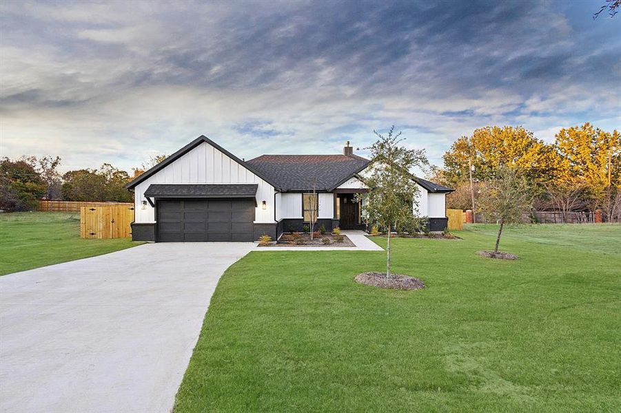 Modern farmhouse featuring driveway, board and batten siding, a garage, and a shingled roof