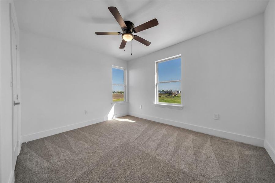 Unfurnished room with baseboards, a ceiling fan, and carpet