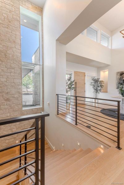 Descending past a flagstone accent wall and steel horizontal railing, the walk-out lower level reveals a world of leisure.