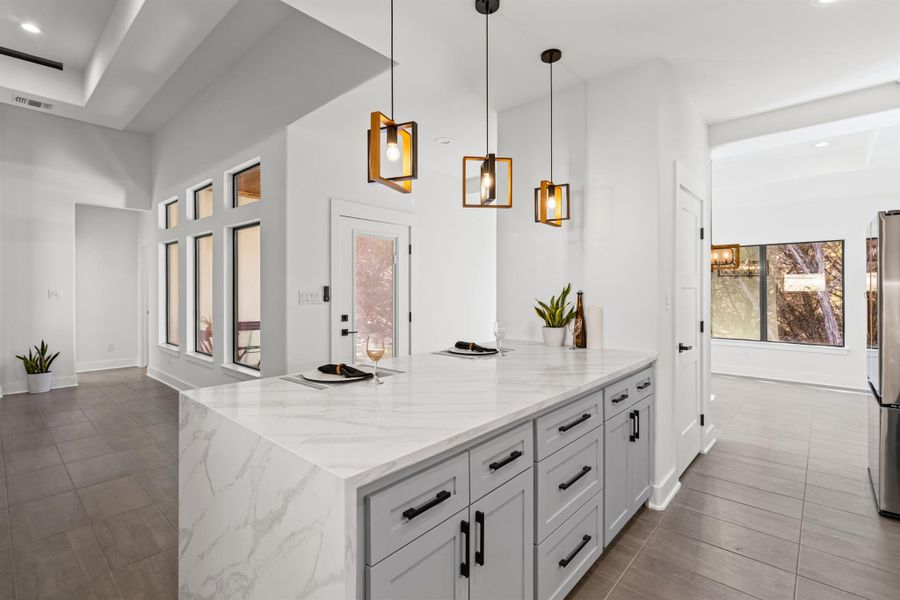 Kitchen with recessed lighting, pendant lighting, light stone counters, and dark tile patterned flooring