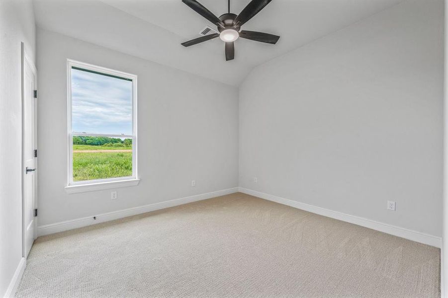 Unfurnished room featuring ceiling fan, baseboards, carpet floors, and lofted ceiling