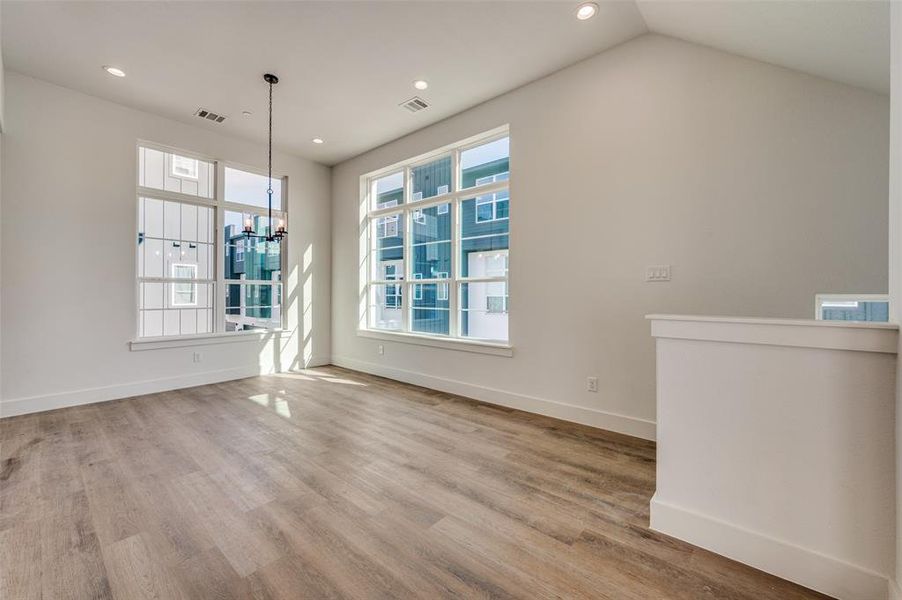 Unfurnished living room featuring a chandelier, hardwood / wood-style flooring, and lofted ceiling