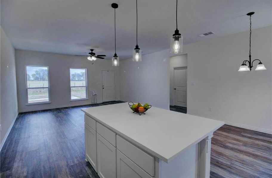 Kitchen featuring open floor plan, white cabinetry, decorative light fixtures, and light countertops Kitchen featuring open floor plan, white cabinetry, decorative light fixtures, and light countertops