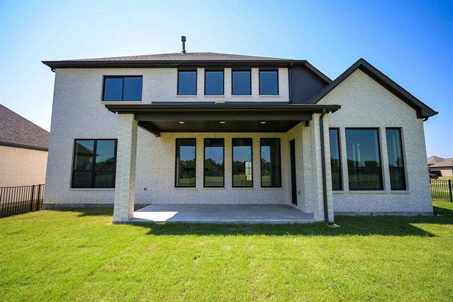 Rear view of house featuring a lawn and a patio