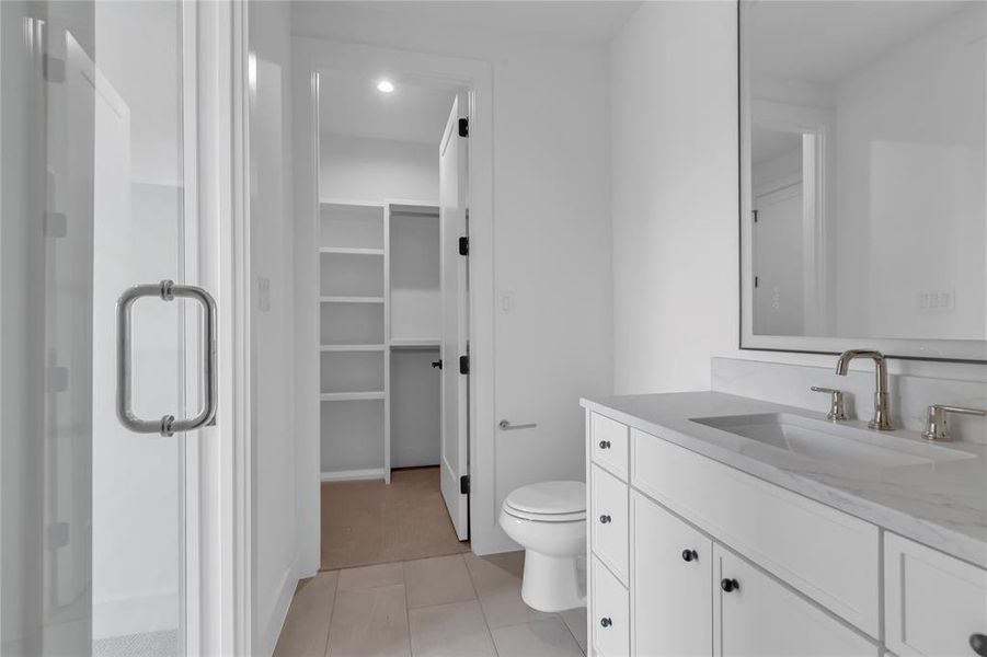 Bathroom with a spacious closet, vanity, a stall shower, and light tile patterned floors Bathroom with a spacious closet, vanity, a stall shower, and light tile patterned floors