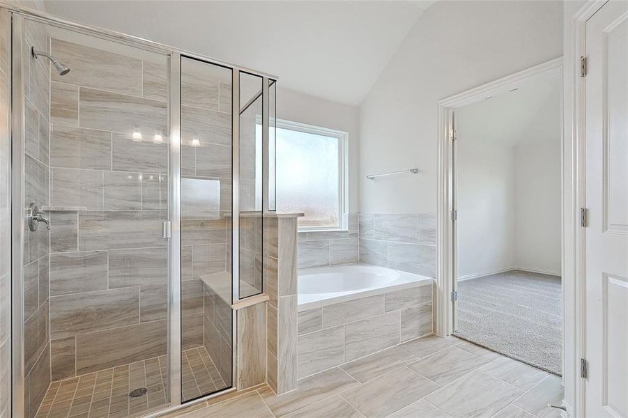 Bathroom featuring tile floors, vaulted ceiling, and separate shower and tub