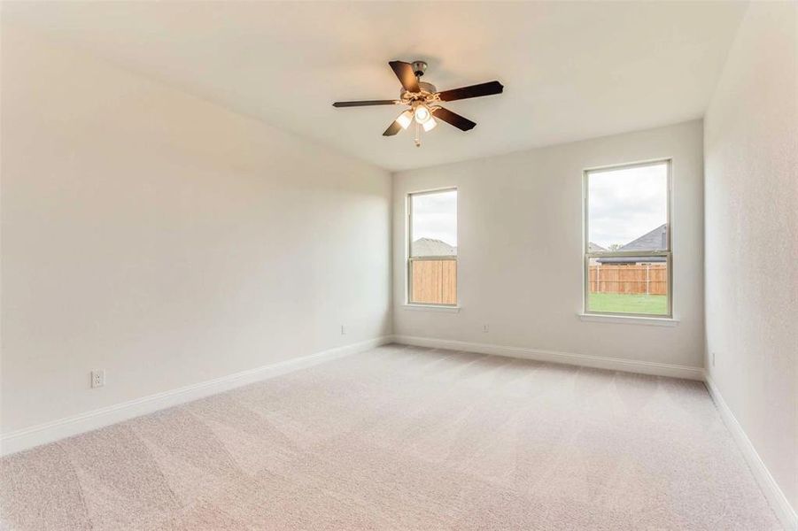 Spare room featuring light carpet, ceiling fan, and a healthy amount of sunlight