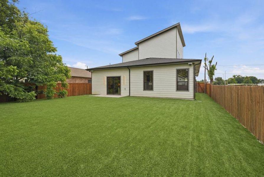 Spacious backyard featuring artificial turf, a privacy fence, and a concrete patio Spacious backyard featuring artificial turf, a privacy fence, and a concrete patio