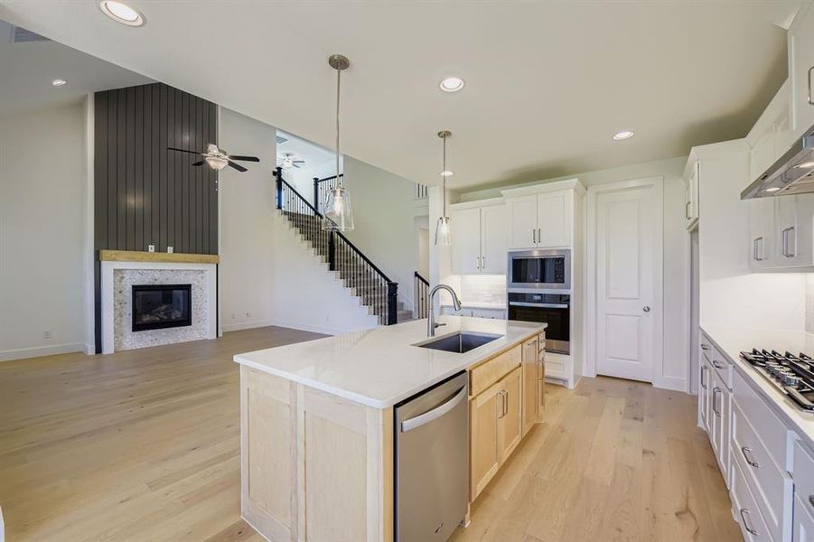 Kitchen with light wood finished floors, recessed lighting, stainless steel appliances, decorative light fixtures, and white cabinets