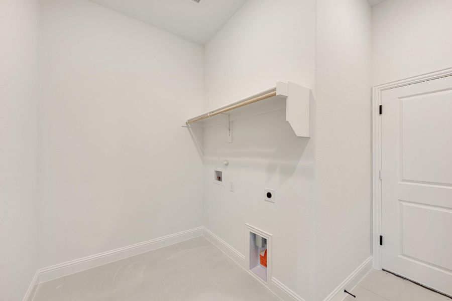 Empty laundry room with white walls, built-in shelf with hanging rod, and washer and dryer hookups Empty laundry room with white walls, built-in shelf with hanging rod, and washer and dryer hookups