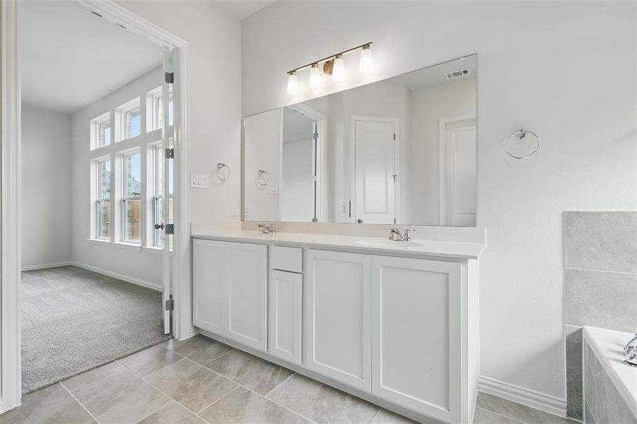 Full bath featuring double vanity and a bath