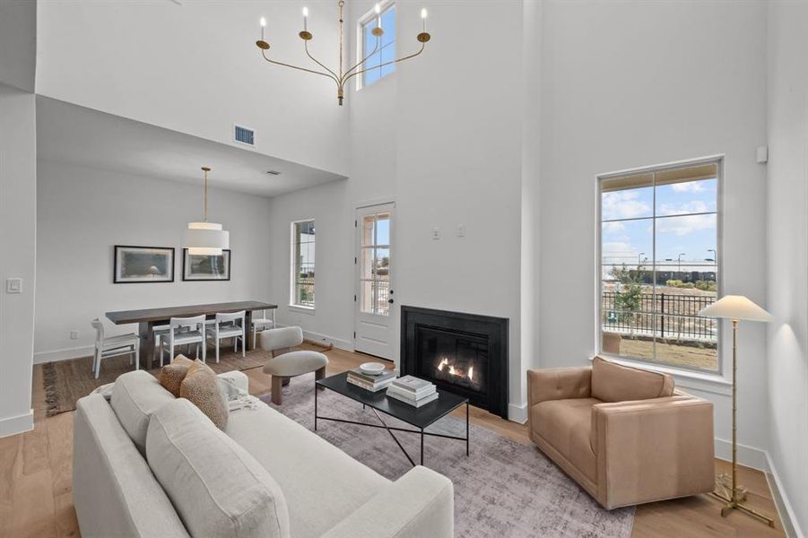 Living room featuring a towering ceiling, a healthy amount of sunlight, and light hardwood / wood-style floors