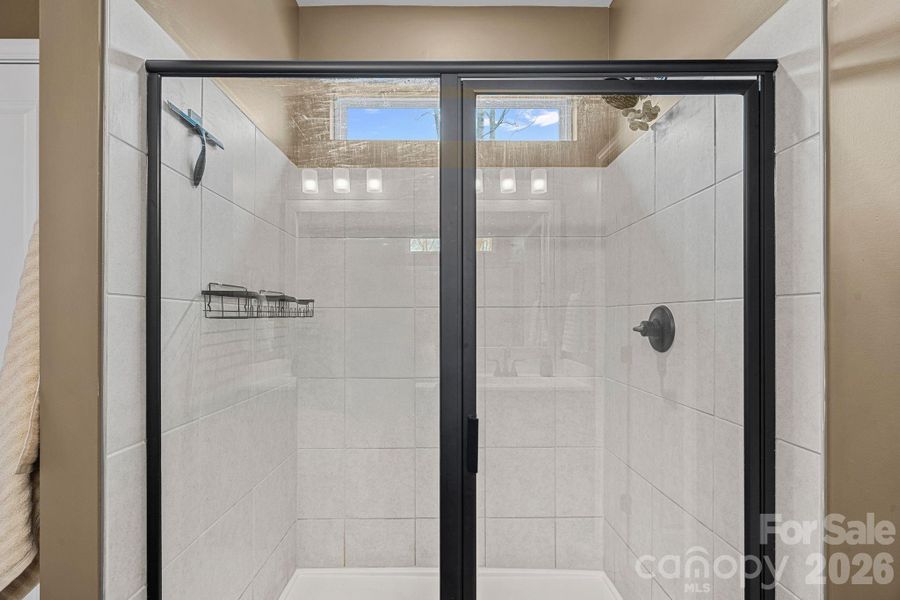 Large shower in the primary bath with transom window. Large shower in the primary bath with transom window.
