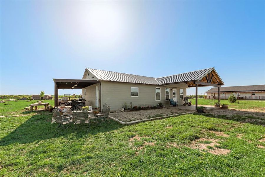 Back of house with a patio area, metal roof, and a lawn