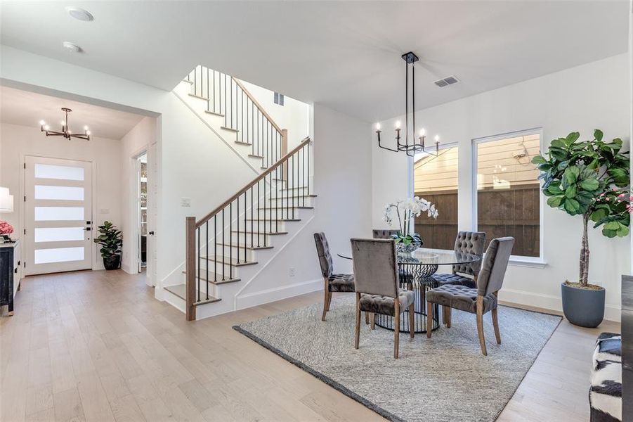 Breakfast/Dining area featuring a chandelier, stairway, plenty of natural light, and light wood-style flooring Breakfast/Dining area featuring a chandelier, stairway, plenty of natural light, and light wood-style flooring