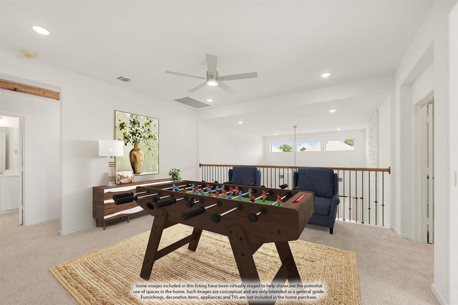 Upstairs loft game room with foosball table, carpet flooring, ceiling fan, and open railing overlooking staircase.