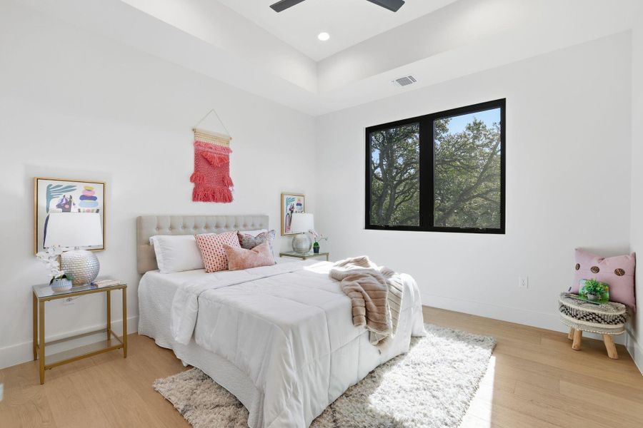 Bedroom featuring light wood-type flooring, a ceiling fan, and a tray ceiling