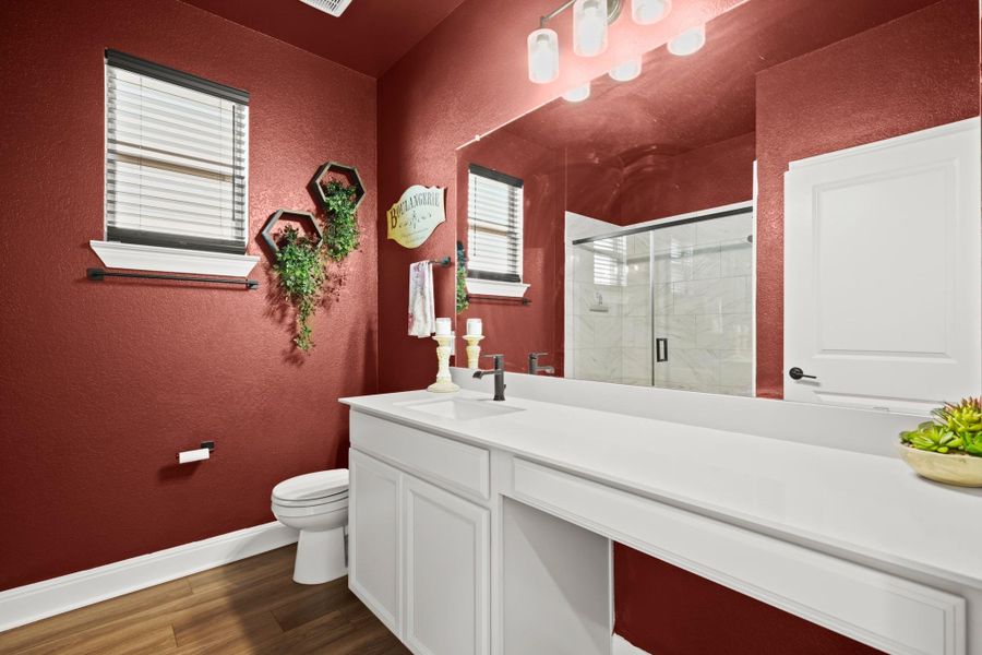 Full bathroom featuring a textured wall, dark wood-type flooring, vanity, and a stall shower Full bathroom featuring a textured wall, dark wood-type flooring, vanity, and a stall shower