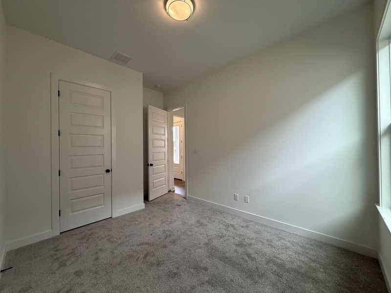 Neutral-toned wall finishes, paneled interior doors with black hardware, and an overhead flush-mount light fixture