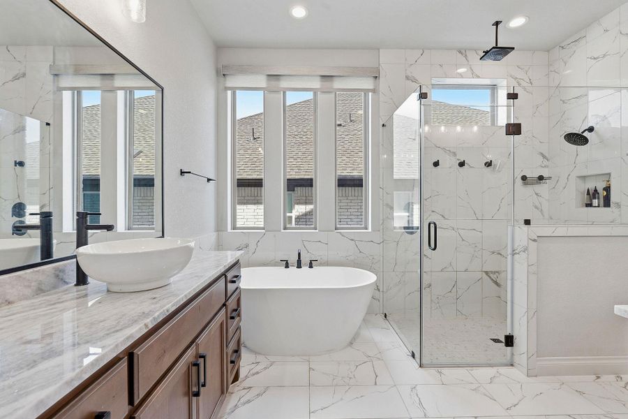 A well-lit primary bathroom featuring a freestanding soaking tub and a spacious walk-in shower. A well-lit primary bathroom featuring a freestanding soaking tub and a spacious walk-in shower.