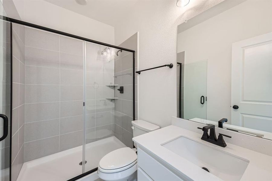 Bathroom with vanity, a shower with shower door, and toilet