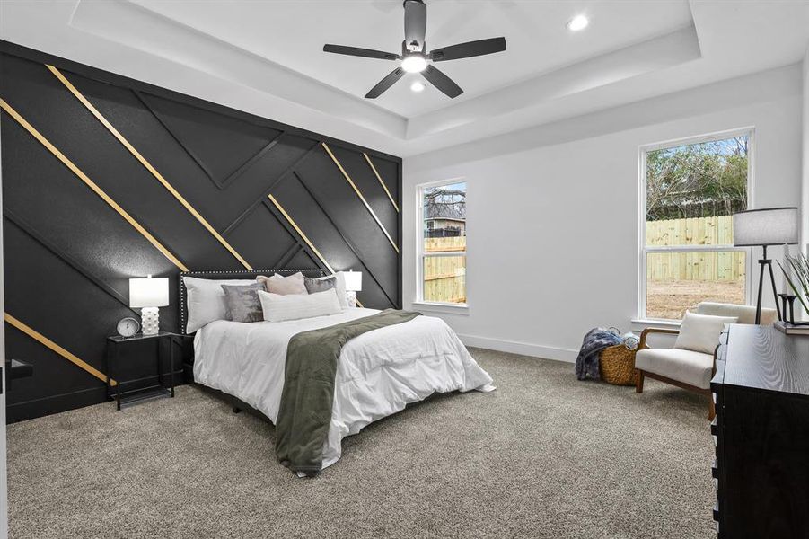 Bedroom featuring ceiling fan, a tray ceiling, and carpet floors