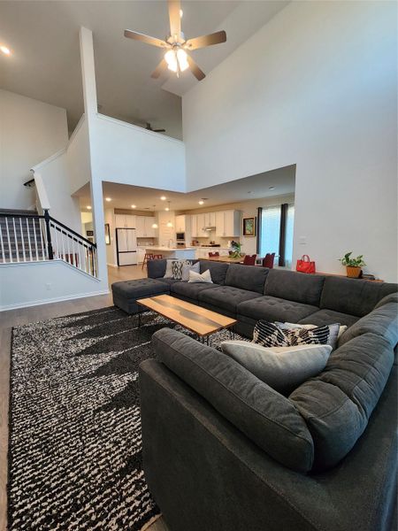 A spacious living room features soaring ceilings and an open-concept design flowing into the kitchen.