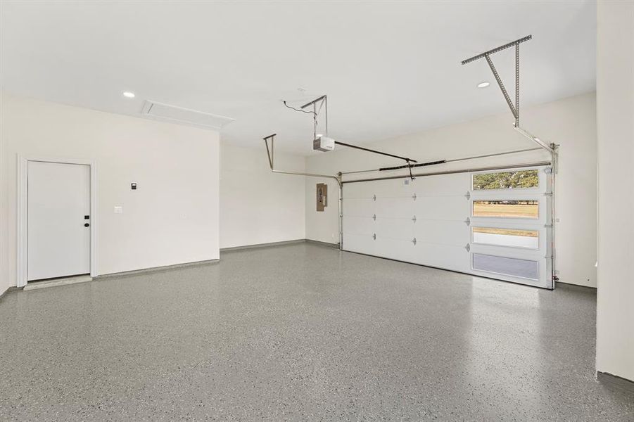 Garage with recessed lighting, electric panel, and a garage door opener
