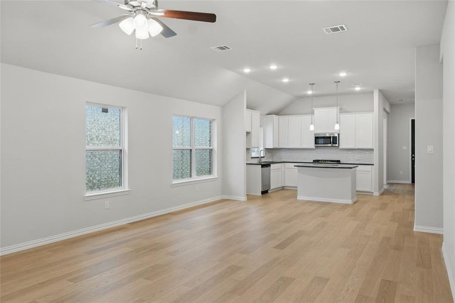 Unfurnished living room with lofted ceiling, light wood-style floors, and ceiling fan Unfurnished living room with lofted ceiling, light wood-style floors, and ceiling fan