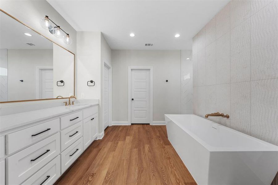 Bathroom with vanity, a freestanding tub, light wood-style flooring, and recessed lighting Bathroom with vanity, a freestanding tub, light wood-style flooring, and recessed lighting