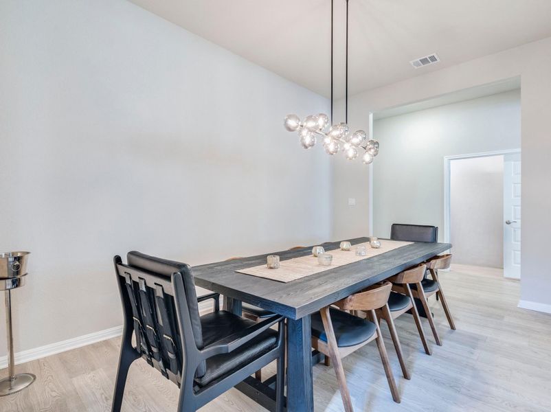 Spacious dining room with light wood flooring & chandalier.