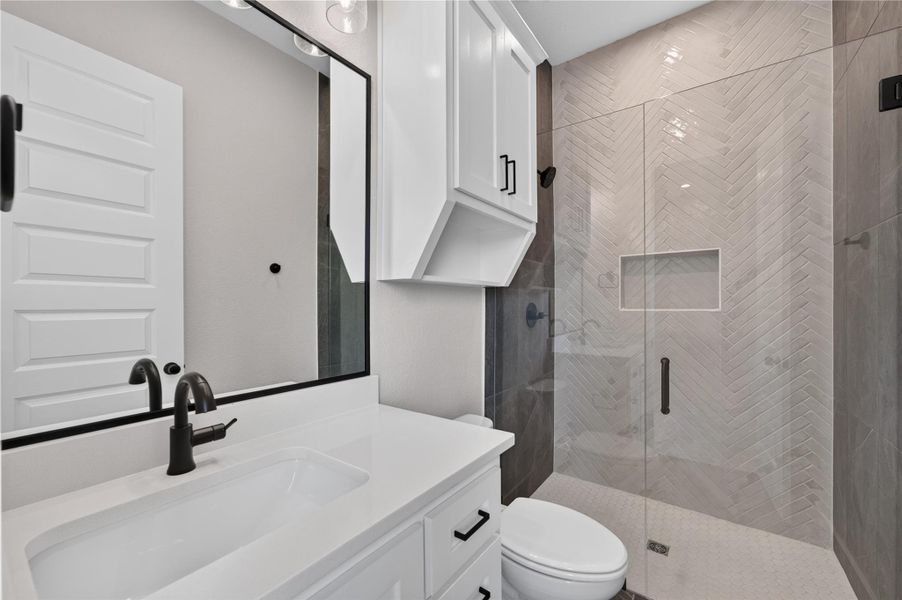 Chevron tiled walls and glass enclosures bring modern elegance to this updated bathroom space.