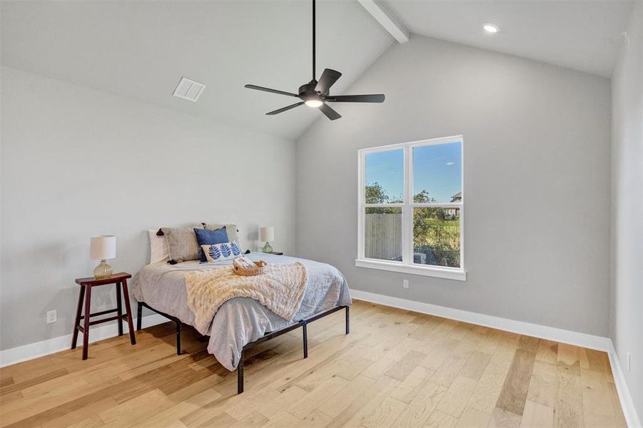 Bedroom with beamed ceiling, light wood finished floors, ceiling fan, and high vaulted ceiling Bedroom with beamed ceiling, light wood finished floors, ceiling fan, and high vaulted ceiling
