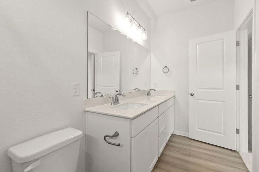 Full bath with double vanity and light wood-style floors