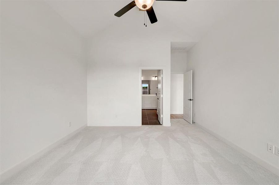 Spacious room featuring vaulted ceilings, light-toned carpet flooring, and a ceiling fan with integrated lighting