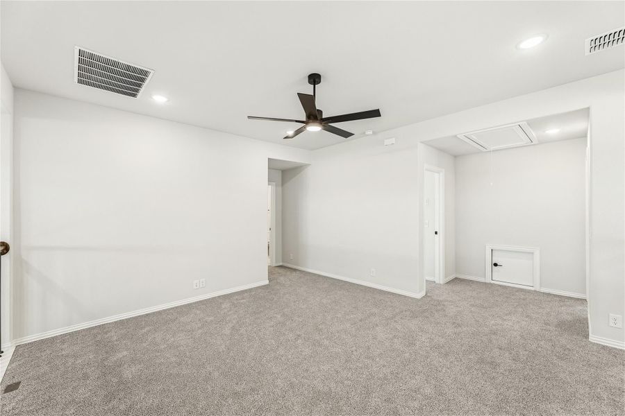 Empty bedroom with gray carpet, white walls, and a dark ceiling fan with recessed lighting