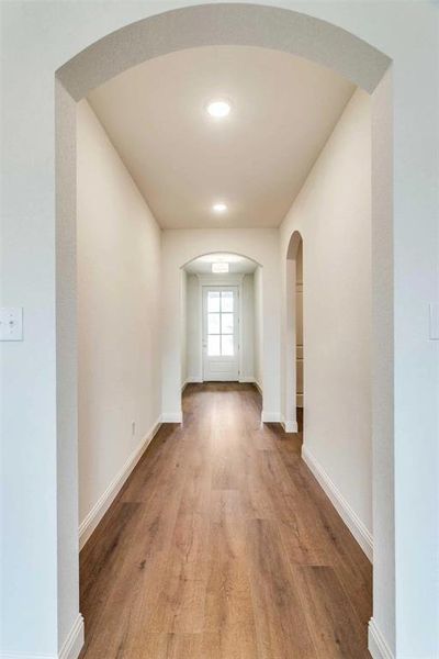 Hall with arched walkways and light wood-style flooring Hall with arched walkways and light wood-style flooring