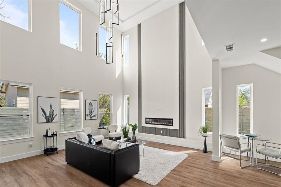 Living room featuring a glass covered fireplace, wood finished floors, and a high ceiling