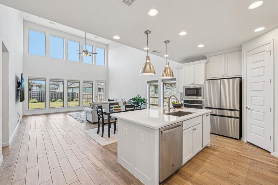 Expansive open-concept living area featuring high ceilings, light wood-style flooring, and large windows providing abundant natural light